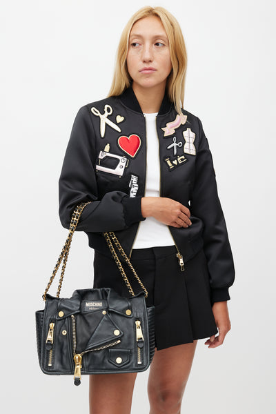 Close-up of black leather and gold hardware on a Moschino Biker Jacket Bag.